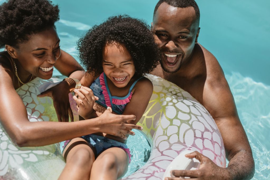 Mother, father, and daughter playing in the swimming pool